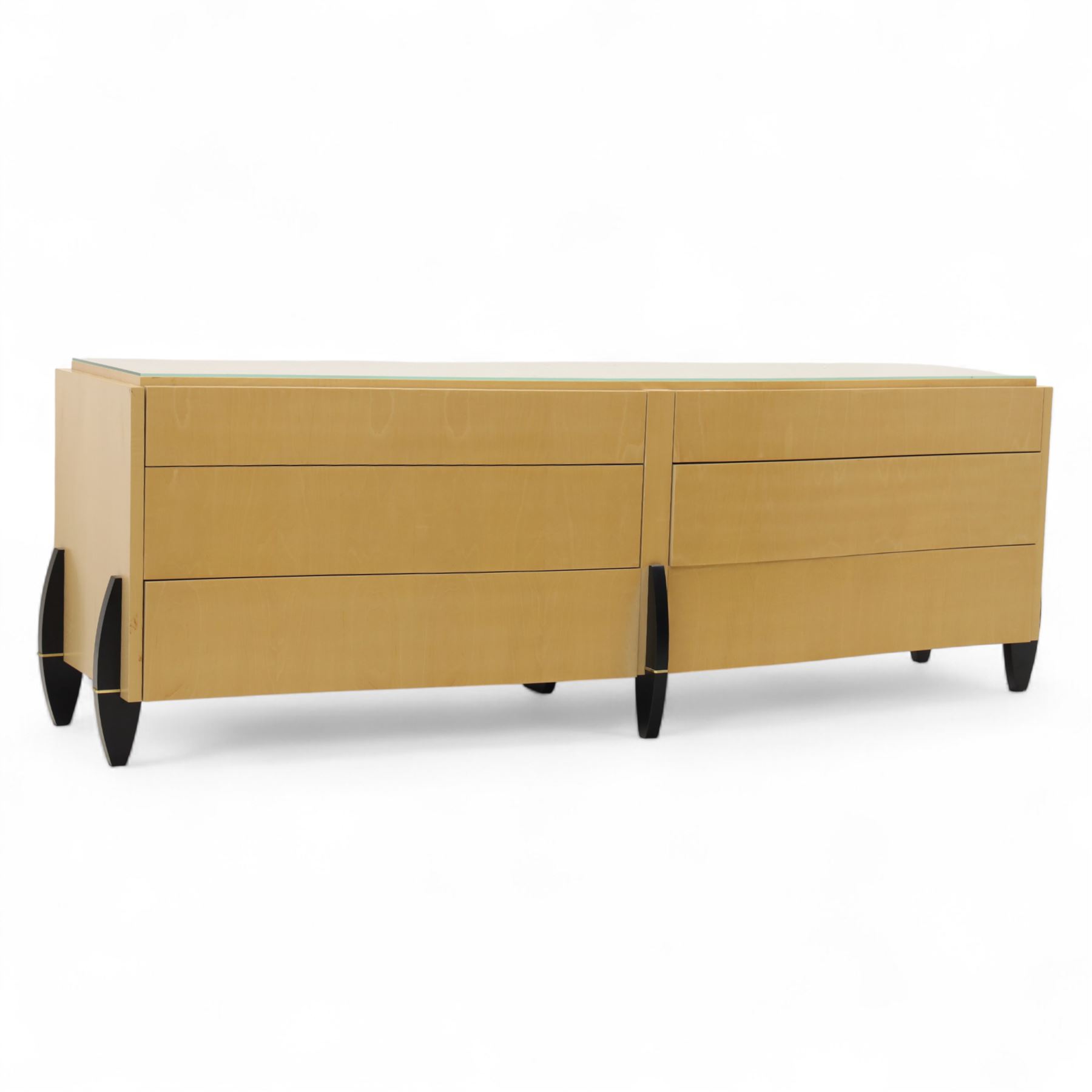 Contemporary maple veneered sideboard, serpentine glass top over six graduating Blum soft-close drawers, raised on curved black and gilt accented supports