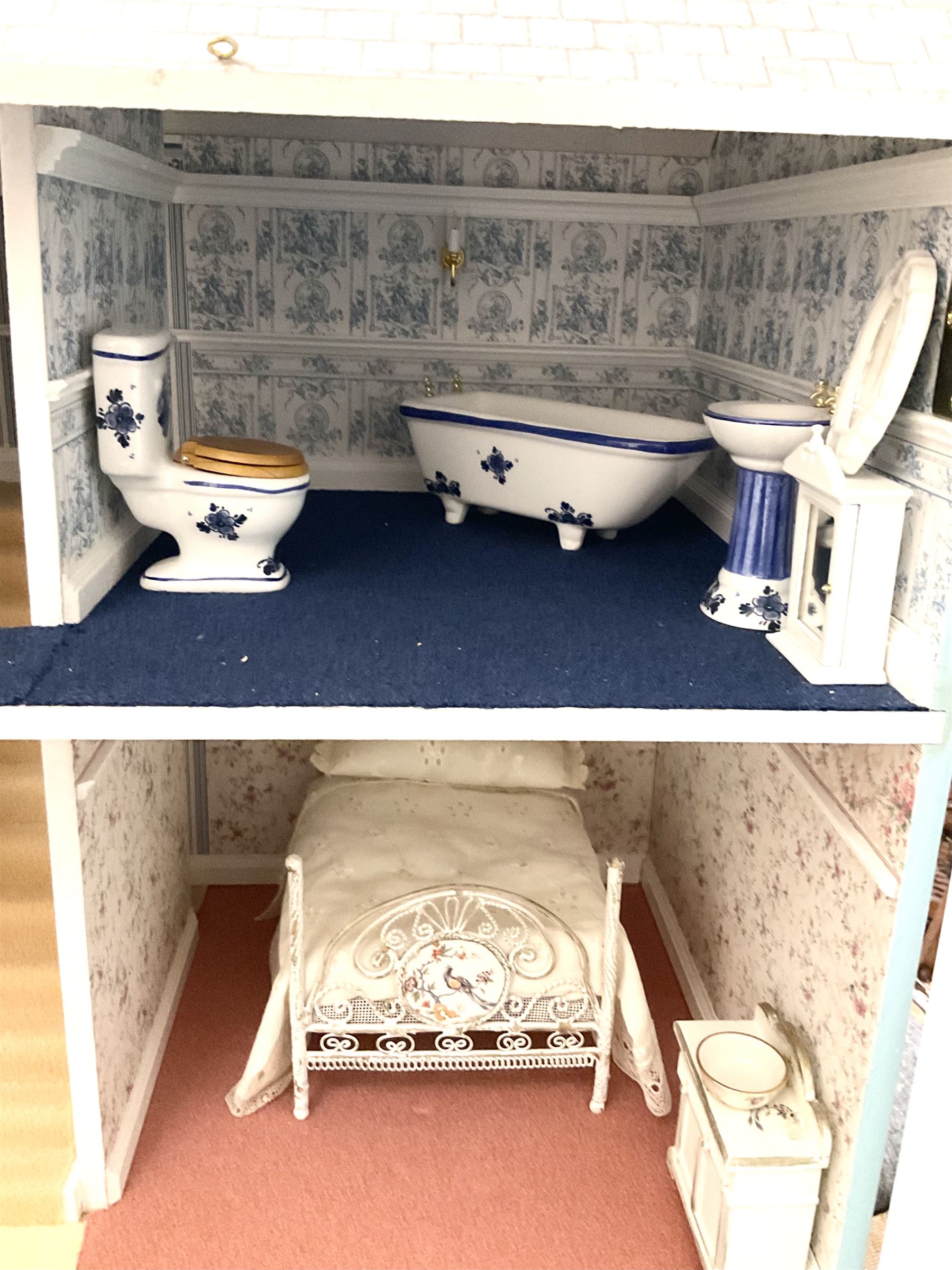 Georgian style wooden double fronted three-storey dolls house with pale blue stucco finish under a faux tiled roof with two chimney stacks, the double hinged front opening to reveal six fully decorated rooms with floor coverings, central staircase, porcelain fitted bathroom, kitchen with deep white sink and Aga cooker, electric lighting with adaptor, fully furnished with French style and other furniture, grand piano etc, and comprehensive range of accessories H82cm W61cm D31cm