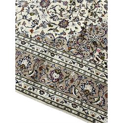 Persian Kashan ivory ground rug, central pointed rosette medallion surrounded by scrolling branches and stylised flower heads, the border with scrolling pattern decorated with palmettes, within guard stripes