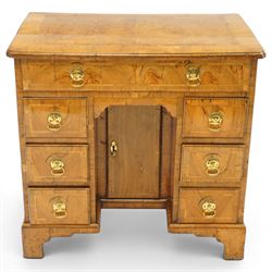 George III figured and burr walnut kneehole desk, the shaped rectangular top with feather and crossbanding surrounded by a moulded edge, fitted with single frieze drawer over three graduating drawers to each side, flanking a central recessed cupboard, lower moulded edge on bracket feet
Provenance: Kirkham Hall