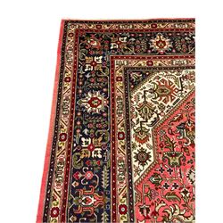 North West Persian pink ground Tabriz carpet, central indigo ground medallion surrounded by stylised plant motifs and trailing foliage, the main border with overall floral design within guard stripes 