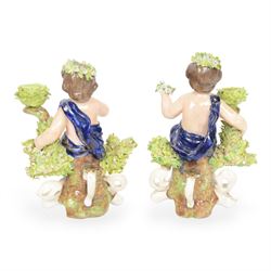 Pair of 19th century Stevenson and Hancock Derby figural chambersticks, each modelled as a seated cherub with arm around foliate encrusted sconce, marked beneath, H18cm