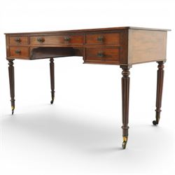 In the manner of Gillows - Regency period mahogany kneehole writing table, rectangular top over central cock-beaded frieze drawer with shaped spandrels, flanked by two graduating drawers to either side, raised on turned and fluted supports terminating to brass cups and castors