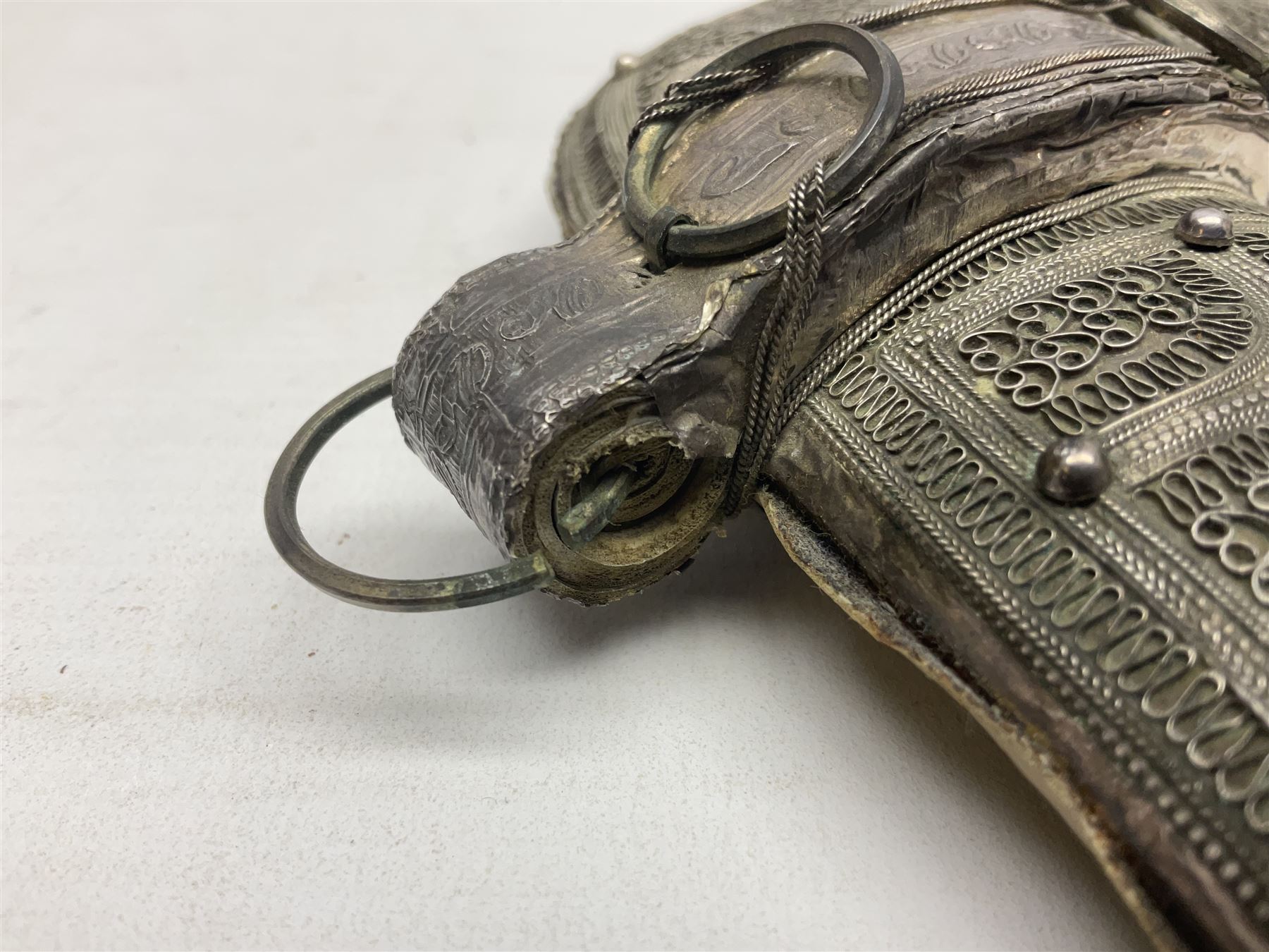 Omani Khanjar dagger, the 12.5cm curved blade with pronounced medial rib to either side, waisted horn style hilt with dome shaped pommel and inlaid pique work; in an intricately filigree decorated white metal scabbard with rings woven into the belt mount L25cm overall