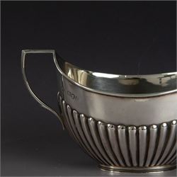 Victorian silver two piece bachelors tea service, comprising teapot and milk jug, of oval part fluted form, the teapot with ebonised wooden handle and finial, hallmarked Josiah Williams & Co, London 1895, together with a silver milk jug and open sucrier, of similar form, hallmarked William Hutton & Sons, London 1898