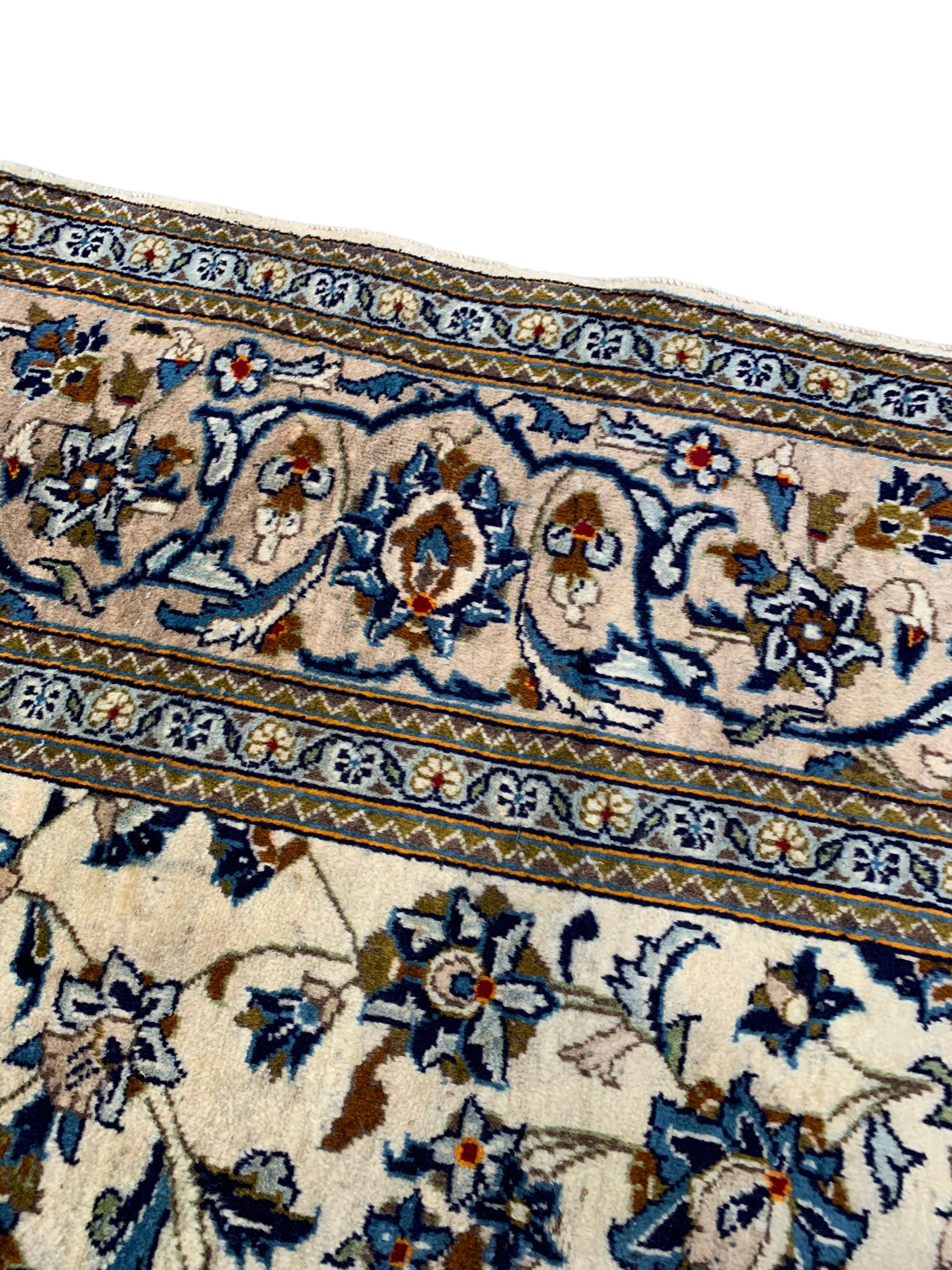 Persian Kashan ivory ground rug, the field decorated with stylised plant motifs and interlacing leafy branches, scrolling border decorated with further plant motifs, floral design guard bands  