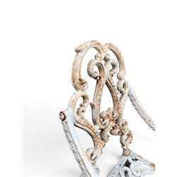 Pair of Victorian cast iron garden chairs, the ornate pierced back of scrolling foliate design, scrolling arm terminals over splayed supports formed of C and S-scrolls, in distressed white painted finish