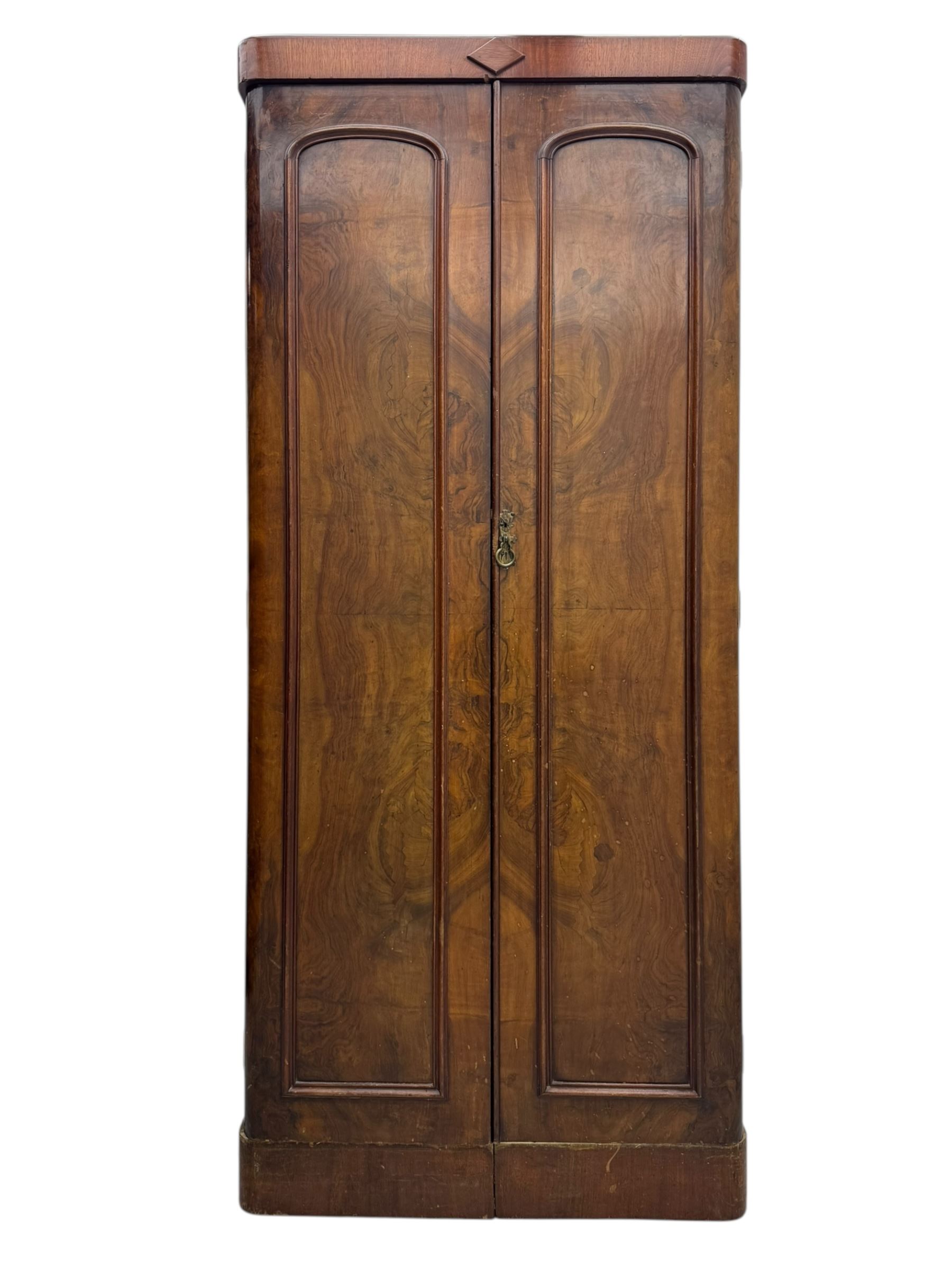 Victorian figured walnut single wardrobe, the moulded cornice with a central diamond motif over a pair of arched panelled doors with striking book-matched veneers, enclosing a fitted interior with hanging rail and hooks, on a plinth base