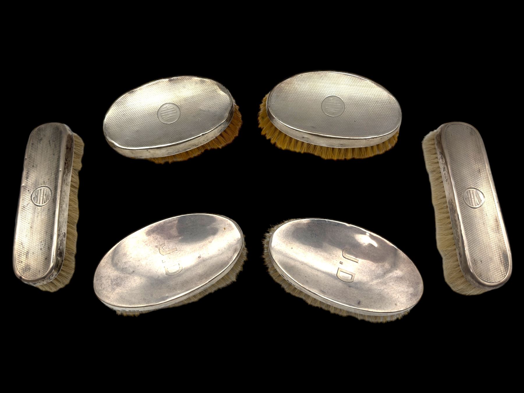 Six silver mounted dressing table brushes, comprising set of four, with engine turned decoration and engraved monogram and a pair of oval brushes with engraved initials, all hallmarked