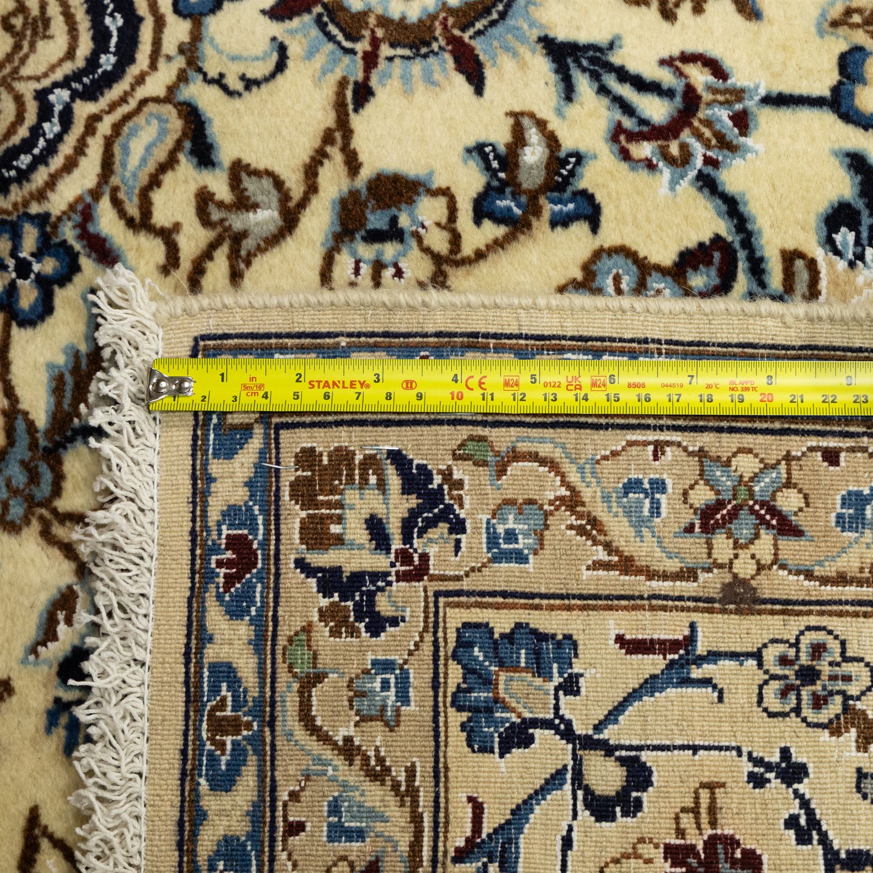 Central Persian Nain hand-knotted carpet, ivory ground, with silk highlights, centred by a shaped floral medallion with pendants, surrounded by scrolling foliate and floral motifs incorporating rosettes, palmettes and delicate vine work in blue, cream and beige tones, enclosed by blue spandrels and an ivory border with repeating palmettes and meandering vines, flanked by floral guard stripes, with cotton fringes