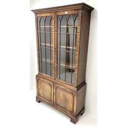 20th century mahogany bookcase, projecting cornice, two doors enclosing three adjustable shelves above two cupboards, bracket supports 
