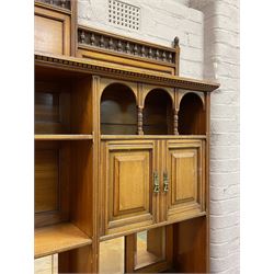 Late Victorian walnut dresser, the raised panelled back fitted with panelled cupboards, shelves and bevelled mirrors, moulded rectangular top over three drawers and cupboards, the left-hand cupboard fitted with two slides and the right-hand cupboard fitted with revolving drinks stand, on turned feet