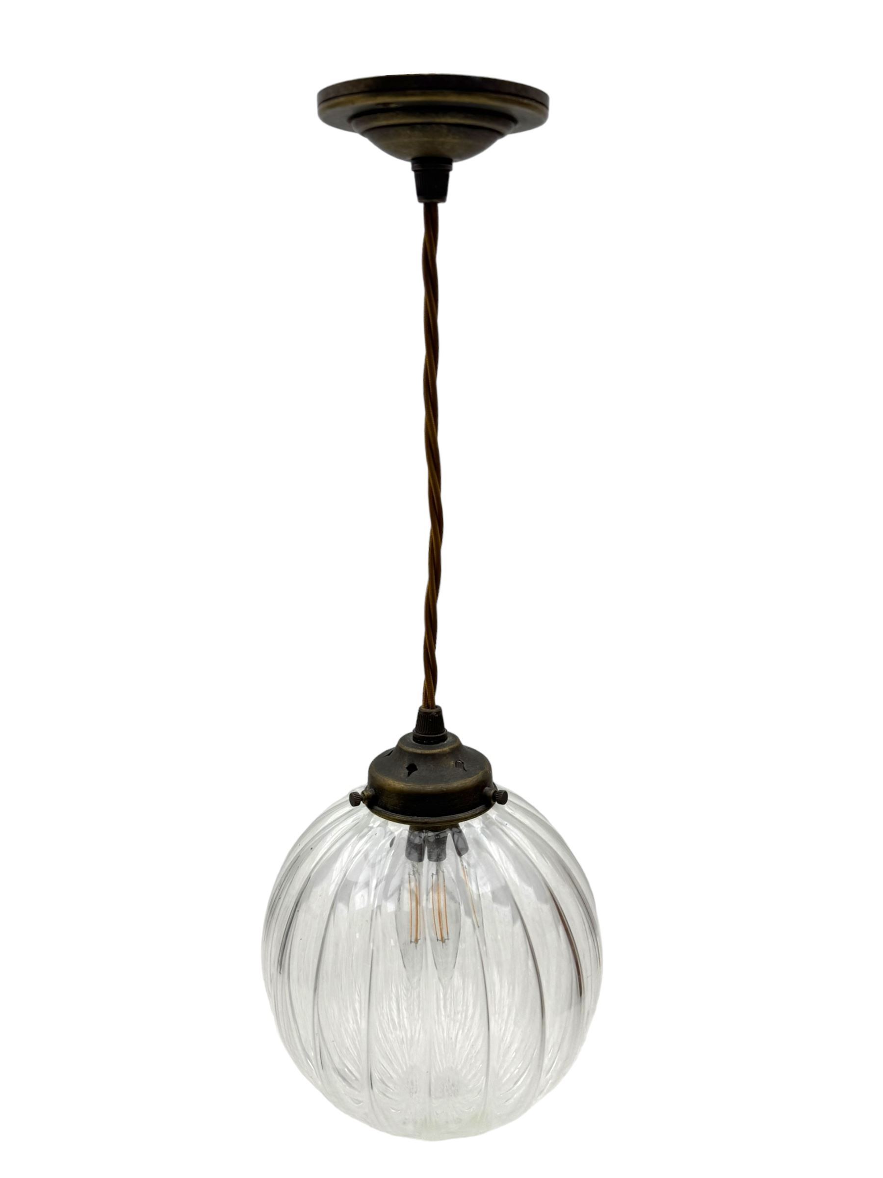 Set of two small and two large pendant lights, each with clear glass spherical shade with moulded swirl pattern, suspended from twisted cords, brass ceiling rose