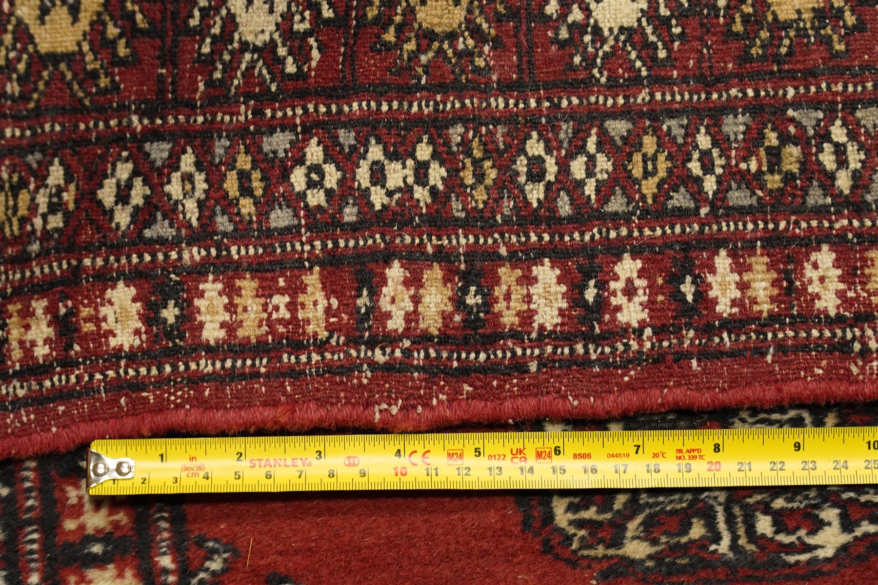 Turkoman hand-knotted rug, madder red ground with two rows of repeating octagonal guls interspersed with geometric motifs, enclosed by multiple geometric and stylised floral borders, with fringed ends