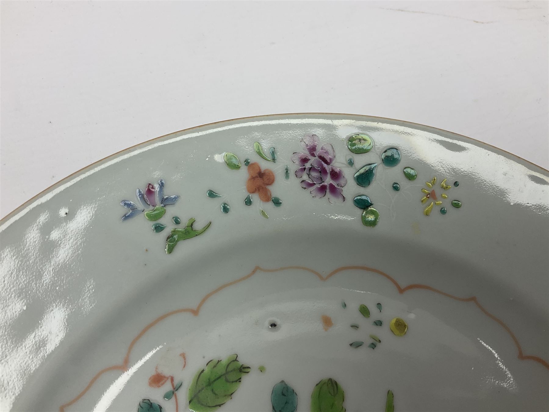 Three 18th century Chinese Famille Rose plates, the first example enamelled with blossoming peonies, rockwork and fence, the other two examples of similar design, decorated with blossoming peonies and sprigs within shaped inner borders, each approximately D23cm