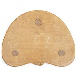 Mouseman - oak three-legged milking stool, dished kidney-shaped seat carved with mouse signature, on three octagonal tapered supports, by the workshop of Robert Thompson, Kilburn