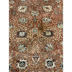 Persian design carpet, rust ground field decorated with large stylised plant motifs surrounded by smaller floral motifs, repeating trailing border