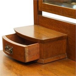 Manner of Liberty & Co. - Arts & Crafts oak dressing chest, the arched swing mirror with roundel-carved frieze and bevelled plate, serpentine-front top with two raised trinket drawers, fitted with two drawers with brass Art-Nouveau poppy handle-plates, on square tapering supports with castors