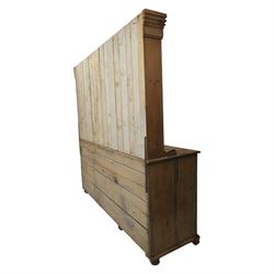 Early 19th century waxed pine farmhouse dresser and rack, the rack featuring two plate shelves and bars above seven drawer base with centre 'dog kennel' recess, raised on turned feet