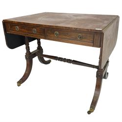 Regency rosewood sofa table, drop leaf rectangular top with rounded corners, fitted with two drawers and two opposing false drawers, raised on dual turned columns terminating in splayed feet united by turned stretcher, on brass cups and castors