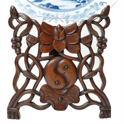 18th century Chinese plate of octagonal design decorated in blue and white with figures by a river with buildings etc W30cm on a 19th century hardwood stand