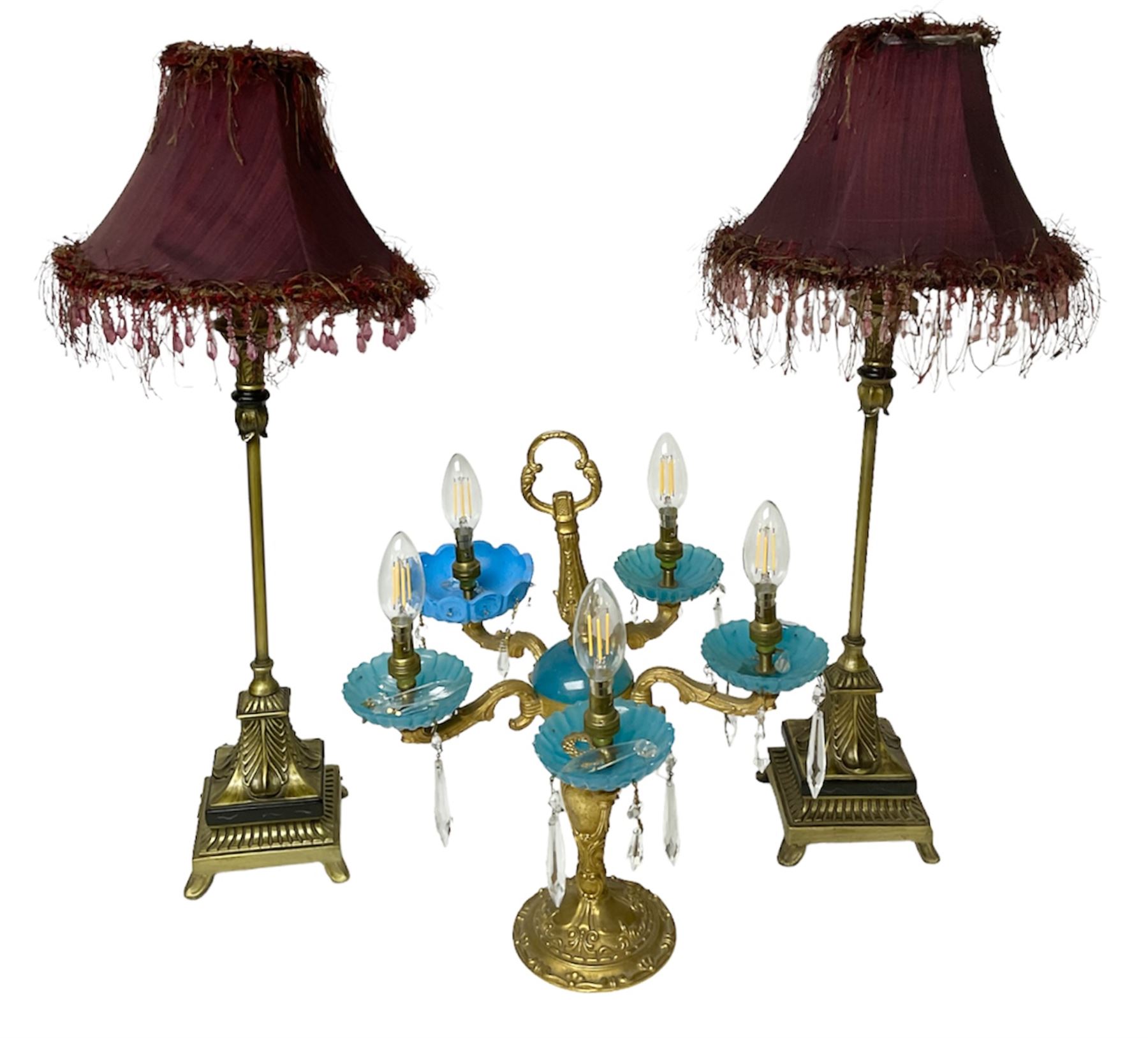 Brass table lamp, modelled as a candelabra with five branches, each with blue glass candle holders with crystal drops, H47cm, together with a pair of cast metal table lamps with acanthus leaf detail, upon a stepped square base, with red fabric feather and tassel shades, H78cm
