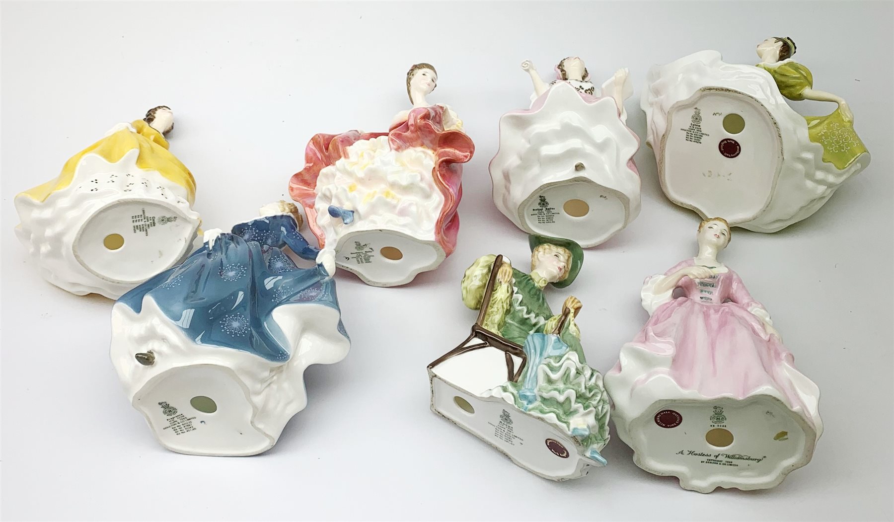A group of seven Royal Doulton figurines, comprising Southern Belle HN2229, A Hostess of Williamsburg HN2209, Ballad Seller HN2266, Coraline HN2307, Fragrance HN2334, Ascot HN2356, Lynne HN2329. (7). 