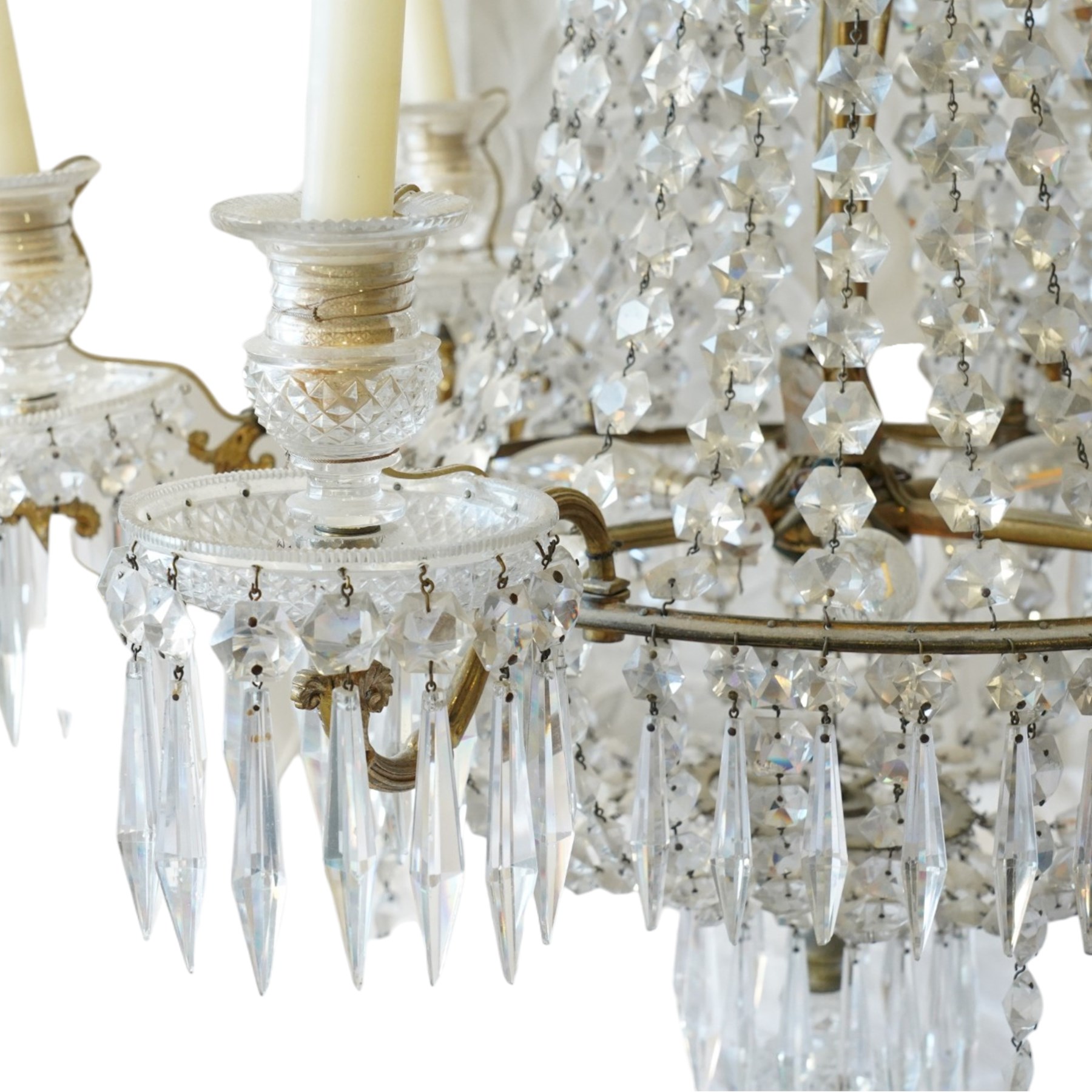 Regency Country House cut-glass and ormolu six light chandelier, the outer shaft with ormolu foliate moulding hung with octagonal and drop pendants, the impressive central shaft with cascading drops of cut-glass, the scroll branches with hob-nail cut candle holders and wax pans, with central similarly cut terminal
Provenance: property of a nobleman