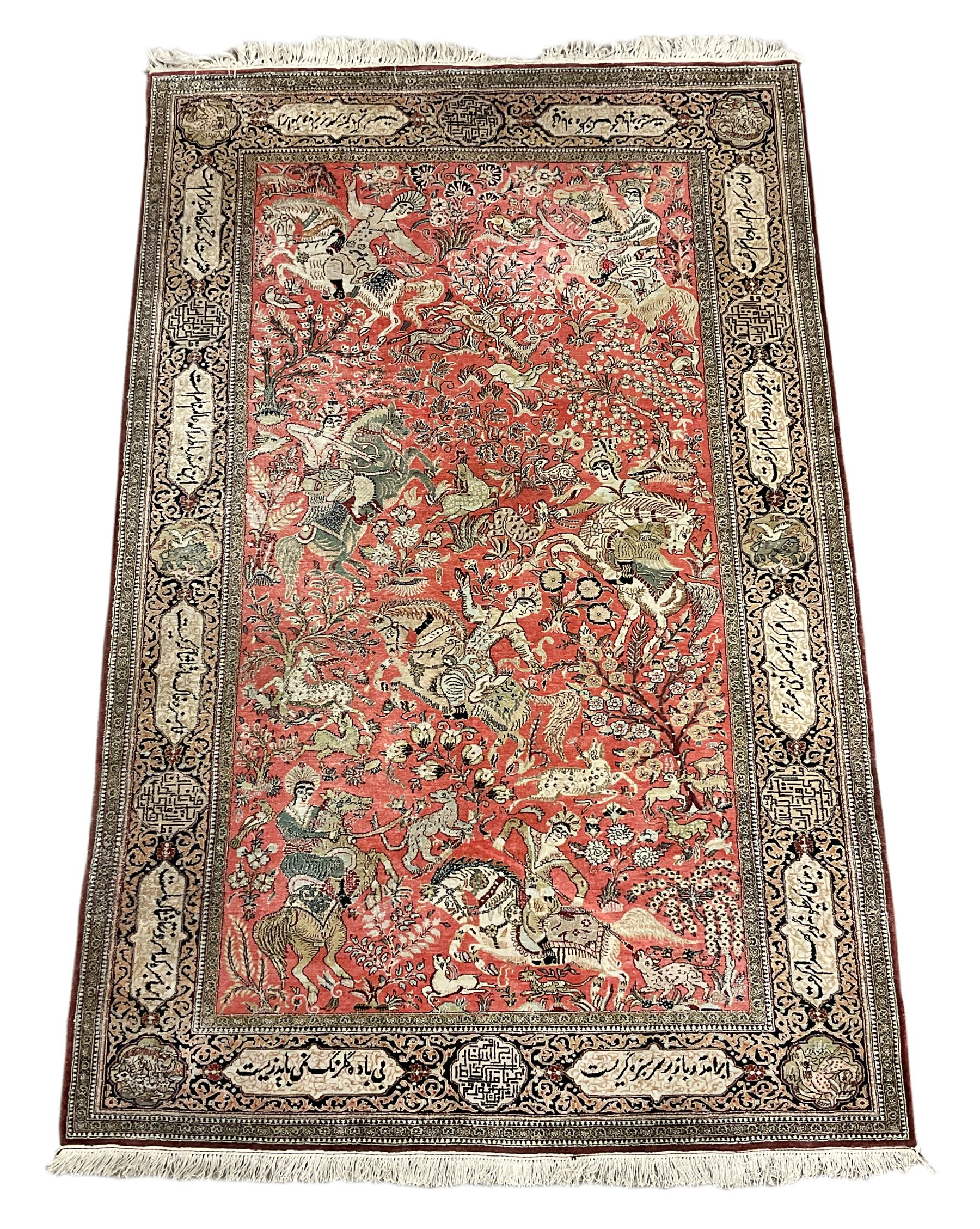 Fine Persian silk and cotton hunting rug, pink ground field depicting hunting scenes, trees and flowers, the border decorated with scrolls and script panel