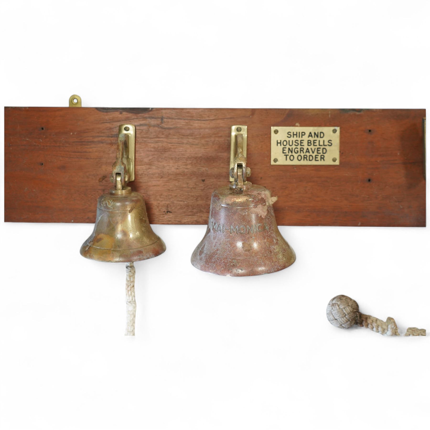 Set of three brass ship bells, each with wall bracket and two with rope pulls, mounted on a rectangular mahogany backboard with brass plaque inscribed ‘Ship and House Bells Engraved to Order’