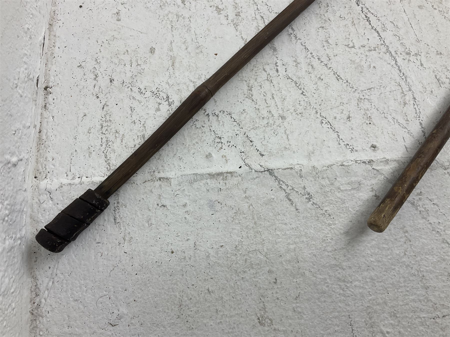 Native long-shafted spear, the large iron head with central medial ridge and decorative neck, on plain circular haft L260cm; and another similar Native long-shafted spear with cane haft L249cm (2)