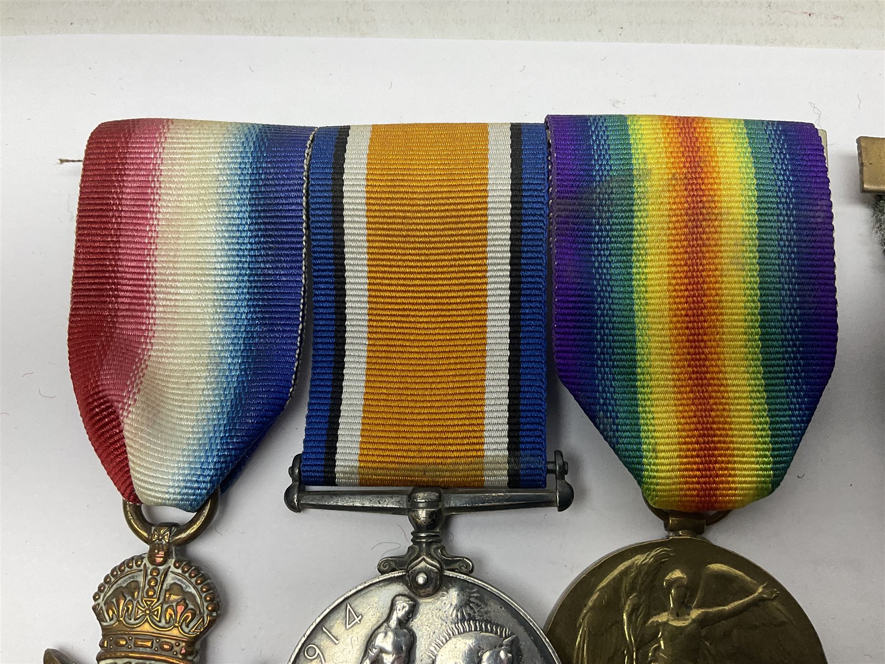 Made-up group of three WWI medals comprising 1914 Star awarded to 23598 Gnr. F. Jefferson R.G.A., British War Medal and Victory Medal with names removed; with ribbons on wearing bar; 1942 Motorist's Medal and small quantity of cap badges, Royalty badges etc