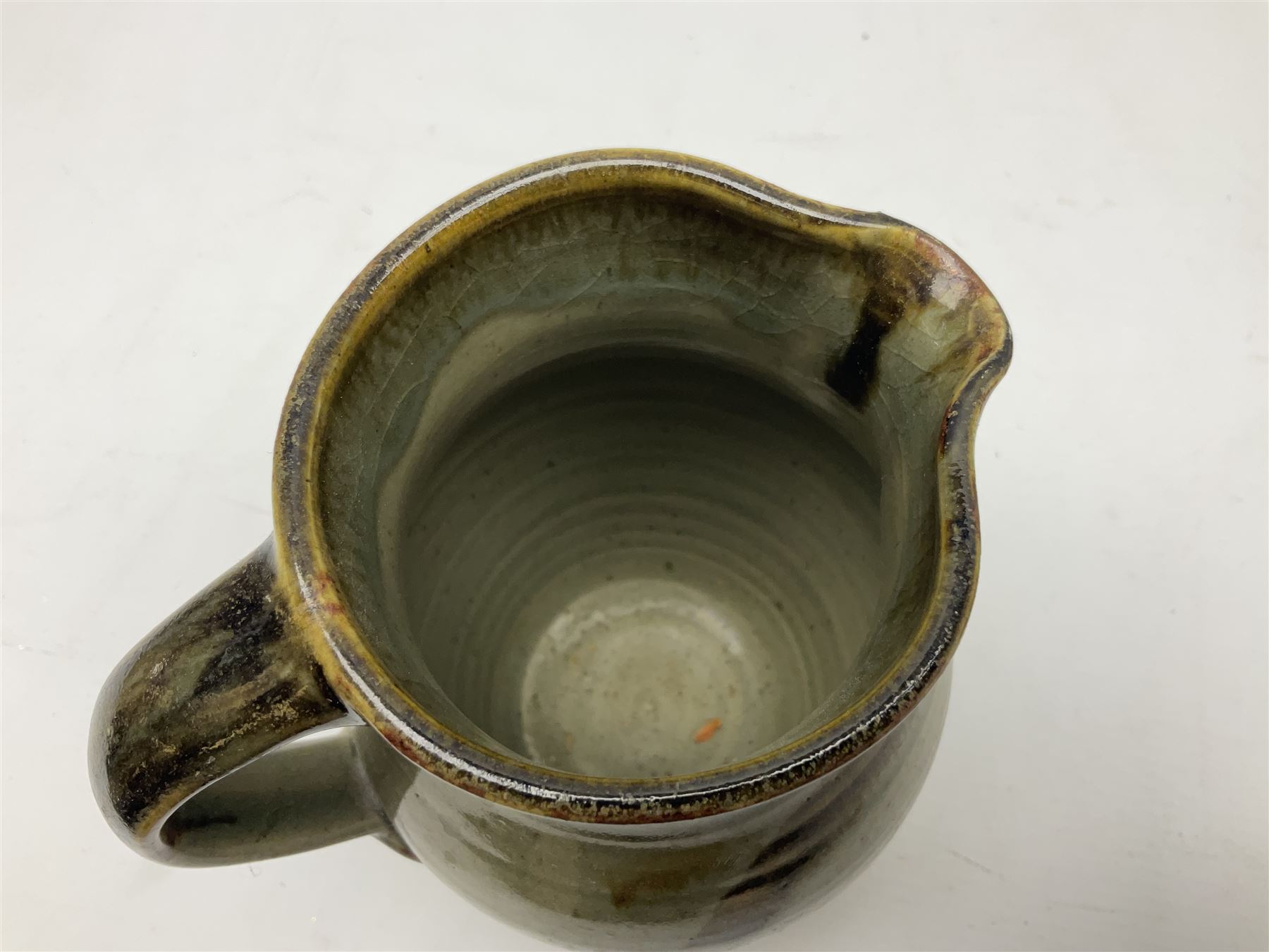 Michael Leach (British 1913-1985) for Yelland pottery; two large glazed stoneware plates with dark brown stylised decoration upon oatmeal ground, together with a jug in merging blue, green and brown, all with impressed marks beneath, largest plate D37cm