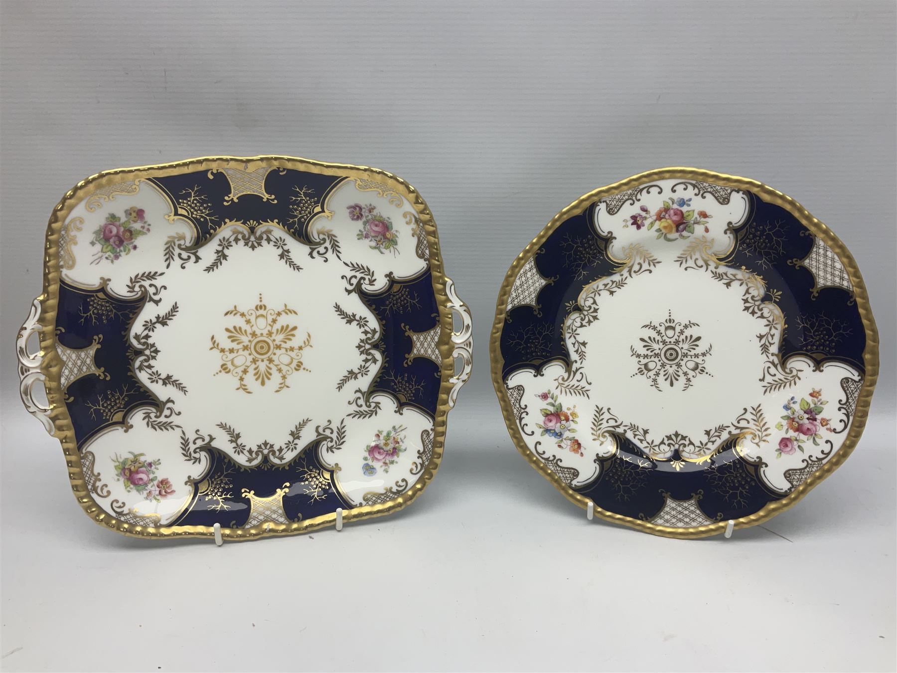 Coalport cobalt blue batwing pattern tea wares, decorated with finely enamelled floral sprays within gilt reserves, comprising teacup trio, coffee can and saucer and other cup and saucer, twin handled cake plate, milk jug and open sucrier, and circular plate retailed by T. Goode & Co London, pattern no Y2665,  all with green Coalport AD 1750 marks beneath, largest W26cm (11)