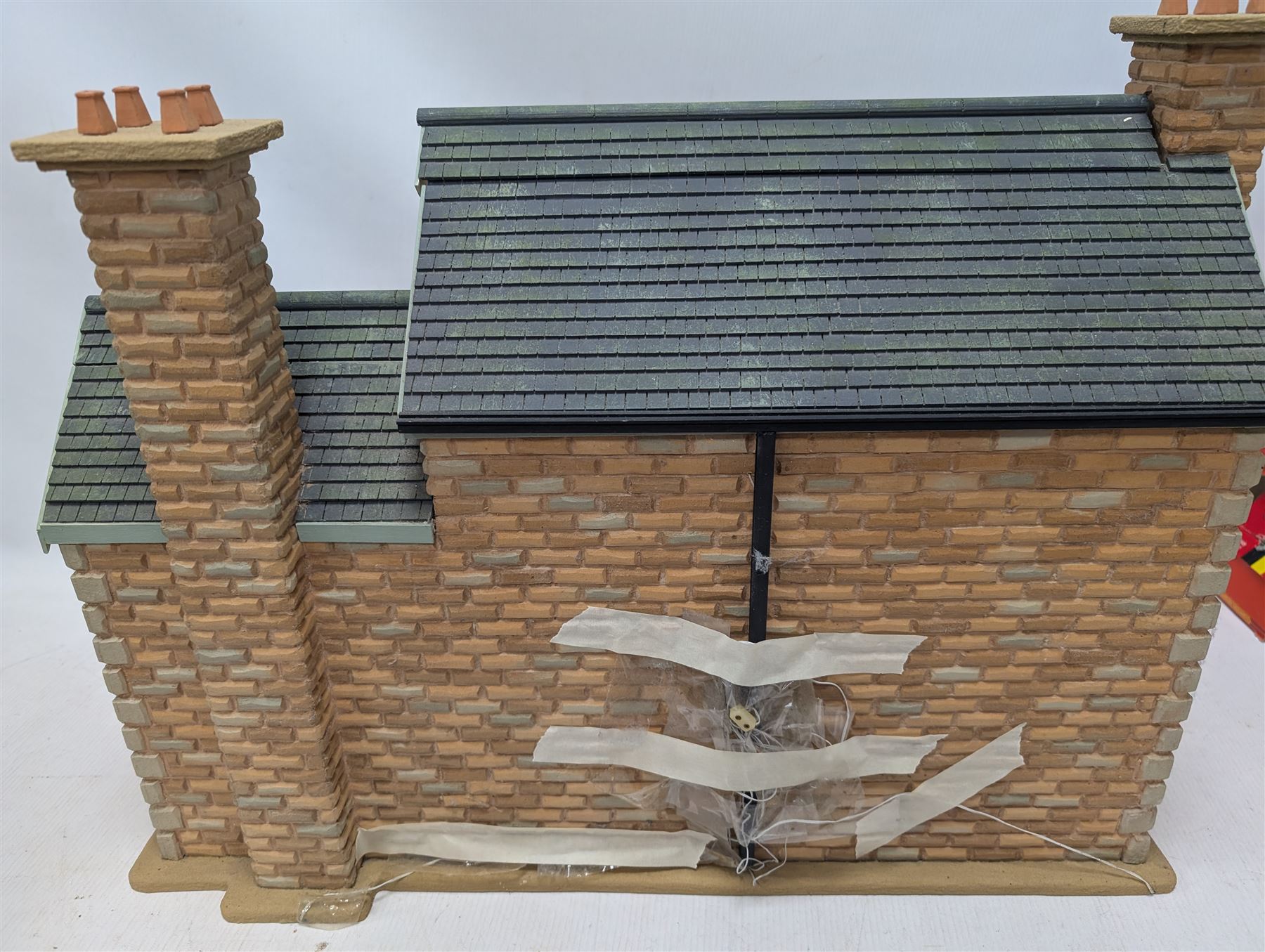 1:24 scale stone effect three-storey cottage dolls house, with green arched door and lattice effect windows, decorated to the interior with wooden floors, wired lighting and fire places, H45cm, W57cm, D26cm