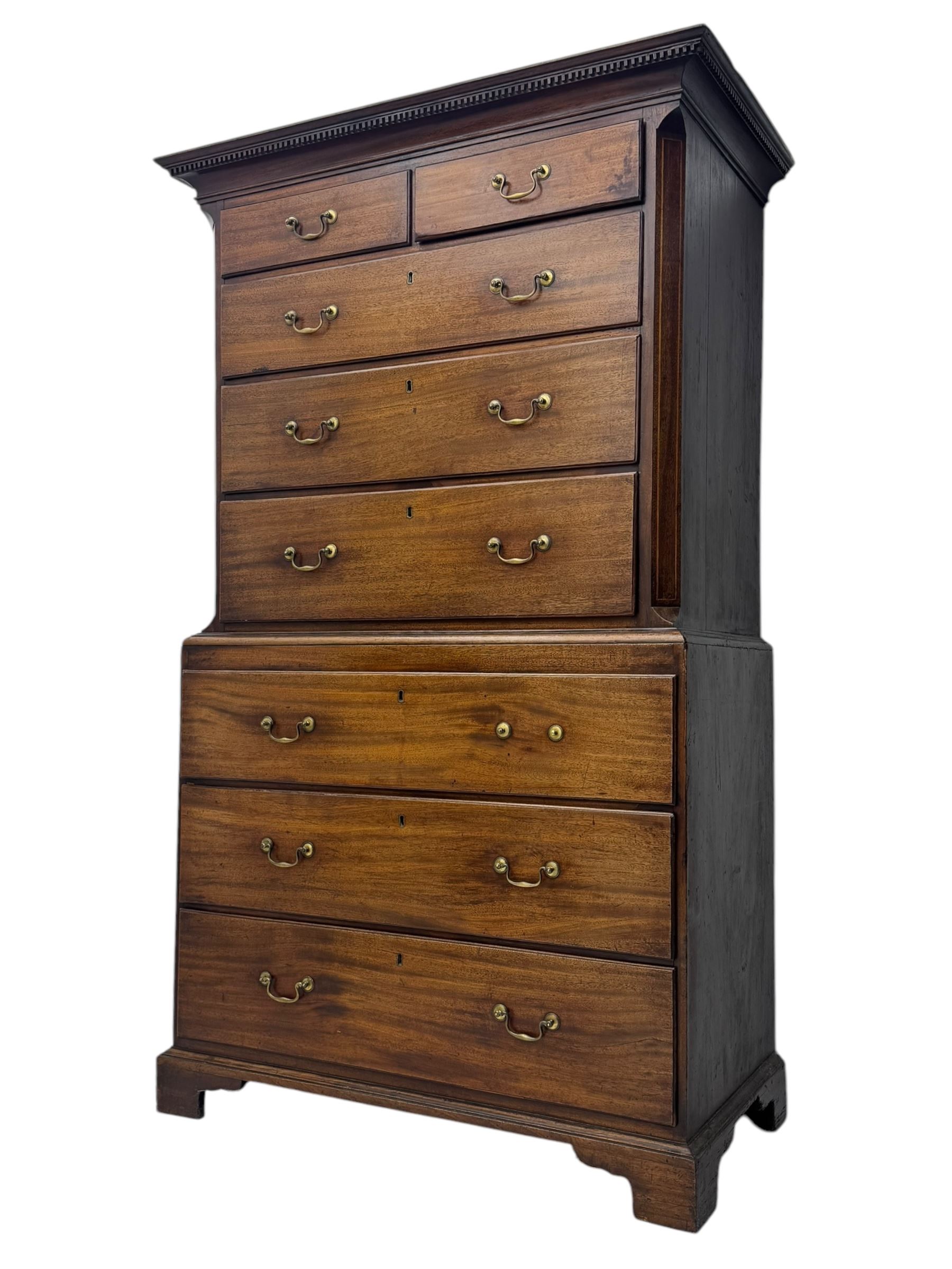 George III mahogany chest on chest, the upper section with two short over three long drawers with swan neck handles flanked by canted corners, inlaid with boxwood stringing below a dentil cornice. The lower section with three long drawers, supported on bracket feet 