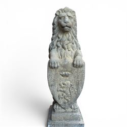 Pair of cast stone Heraldic lions, modelling in upright standing poses with flowing mane, each clasping an Armorial shield moulded with a crowned lion in their forepaws, raised on rectangular pedestals