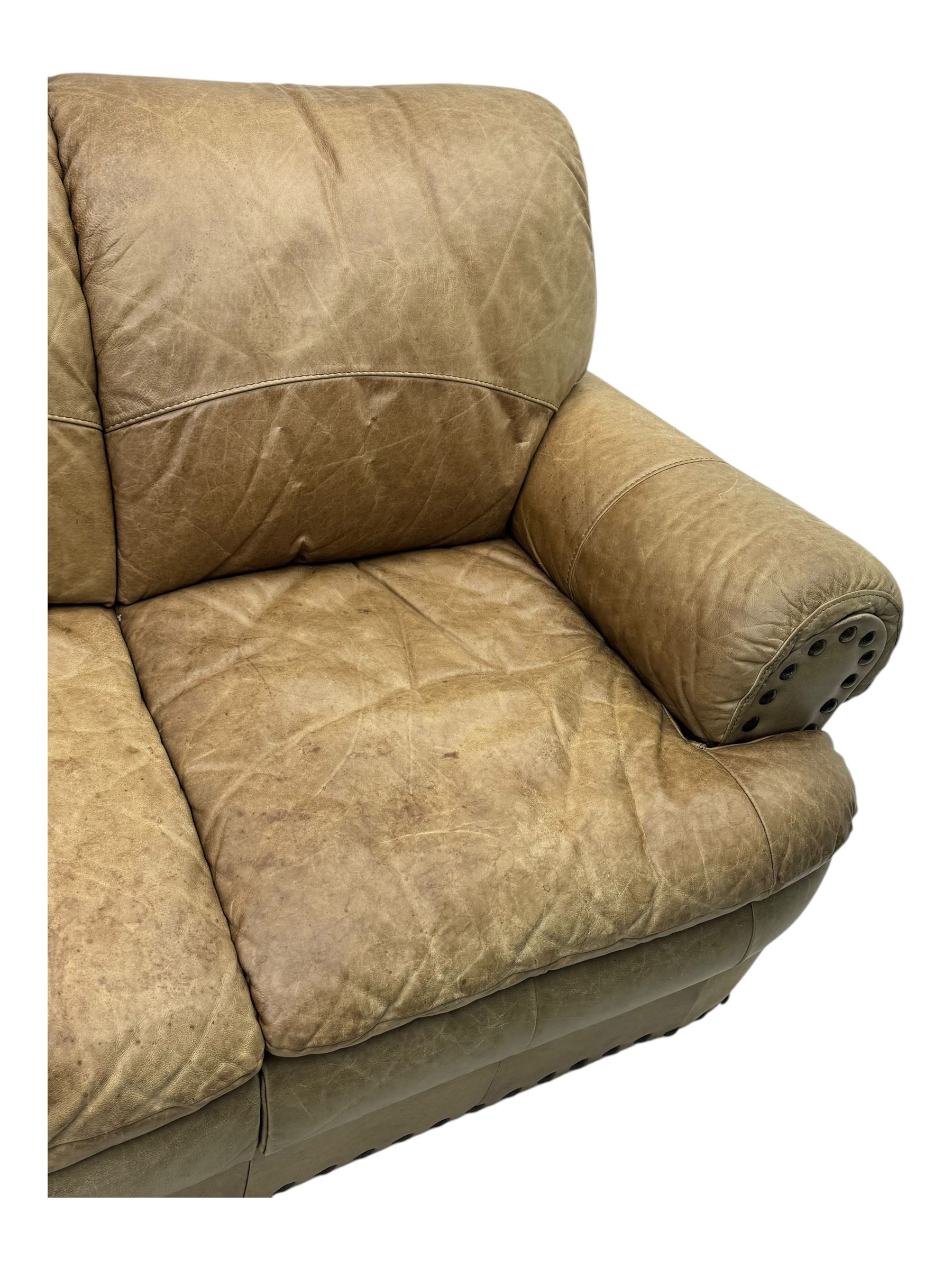Contemporary three-seat sofa, upholstered in stitched brown leather with brass studwork decoration, rolled back and arms, raised on turned supports