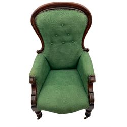 Early Victorian armchair, the shaped back buttoned in green upholstery, scroll carved arm terminals, turned and carved supports with brass castors 