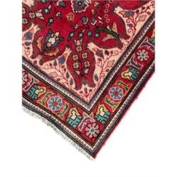 Persian Azerbaijan crimson ground rug, the field decorated with central floral motif and surrounded by trailing floral branches, enclosed within a shaped outer band with further floral decoration, the border with repeating flower heads, geometric guard stripes