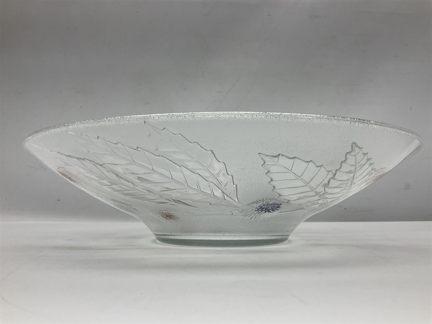 Two French pressed glass bowls of shallow circular form, relief moulded with flowers and foliage, together with a matching charger, largest bowl D34cm  