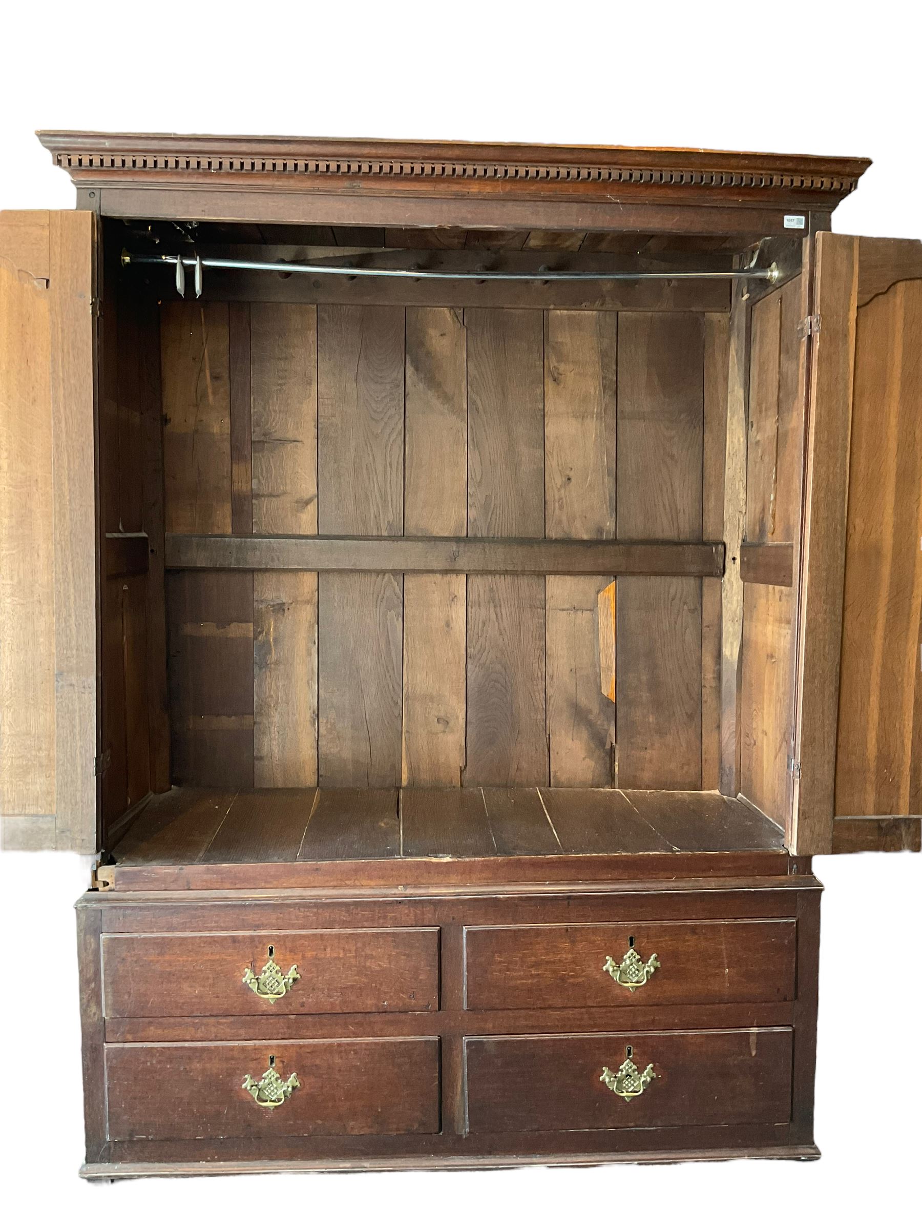 George III oak press cupboard, dentil cornice over two arch fielded panel doors, the base fitted with four drawers with pressed brass handle plates