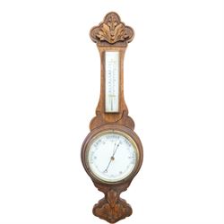 Late Victorian carved oak aneroid barometer, the foliate crest above a glazed thermometer ...