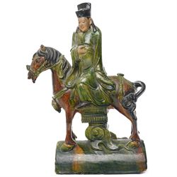 Chinese Ming dynasty Sancai Glazed Roof Tile, modelled as a dignitary on horseback, dressed in a long robe with voluminous folds, wearing an official's cap, upon a half cylinder tile, H40cm