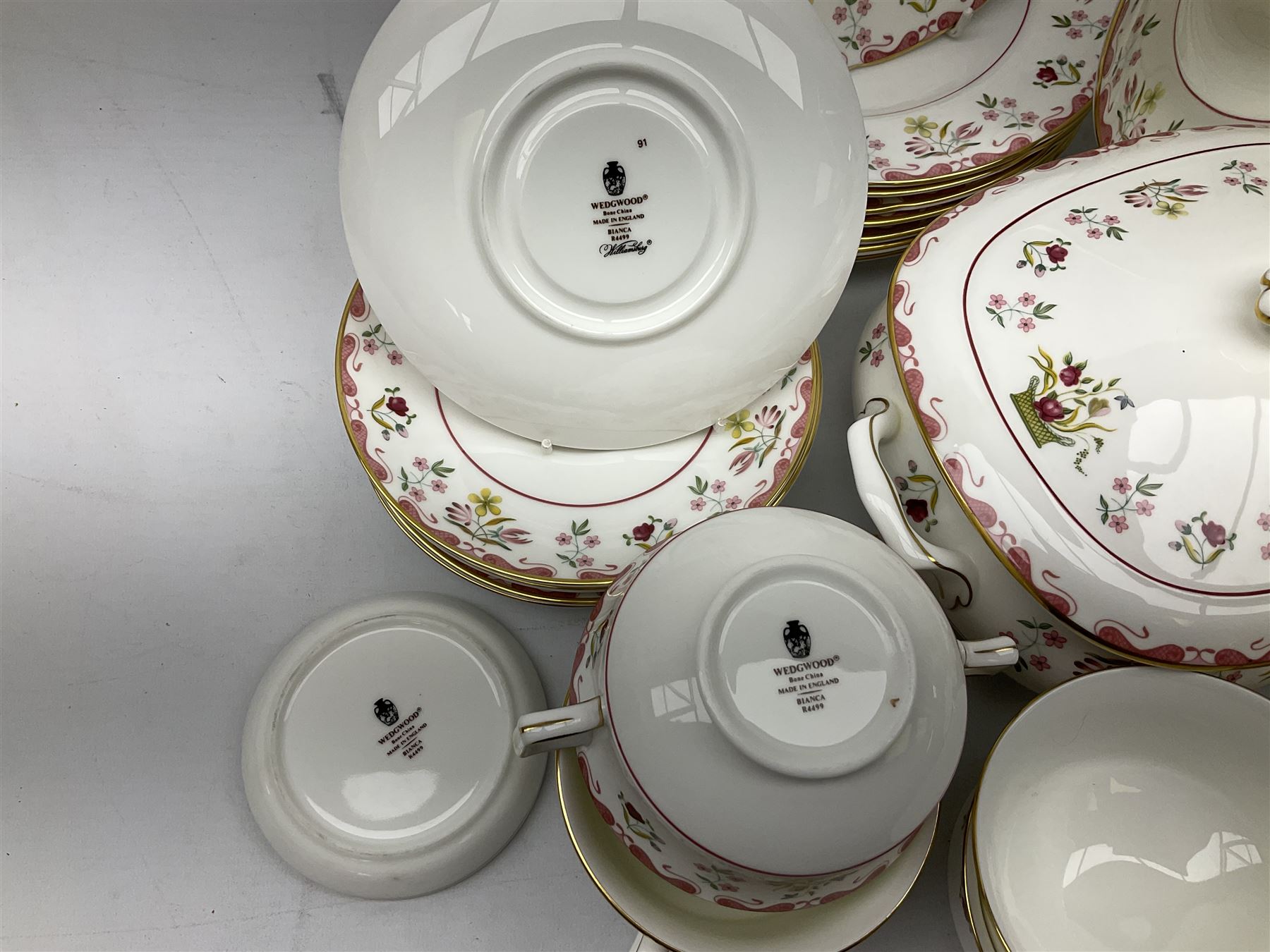 Wedgwood dinner service decorated in the 'Bianca' pattern, to include eight dinner plates, eight bowls, eight side plates, eight twin handled souo bowls, eight soup bowl saucers, eight teacups, eight teacup saucers, six dessert plates and two larger, two twin handled lidded tureens, milk jug, two sauce boats, salt and pepper shakers, oval serving  plate, twin handled sandwich plate, covered sucrier, small rectangular dish and two small circular dishes, all with printed stamp mark beneath
