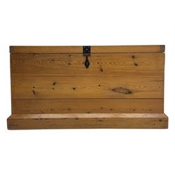 Contemporary polished pine blanket chest, the hinged planked lid with iron strap hinges and clasp fitting, plain boarded sides, fitted with blackened metal drop handles, on a moulded plinth base