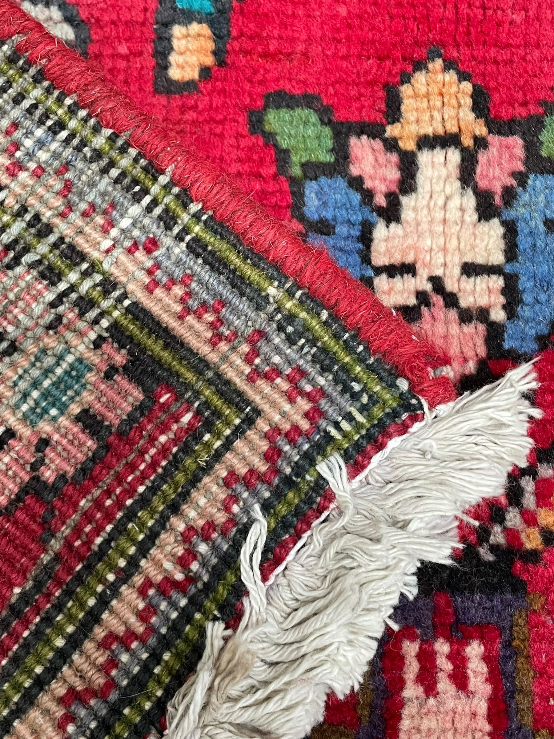 Persian Azerbaijan crimson ground rug, the field decorated with central floral motif and surrounded by trailing floral branches, enclosed within a shaped outer band with further floral decoration, the border with repeating flower heads, geometric guard stripes 