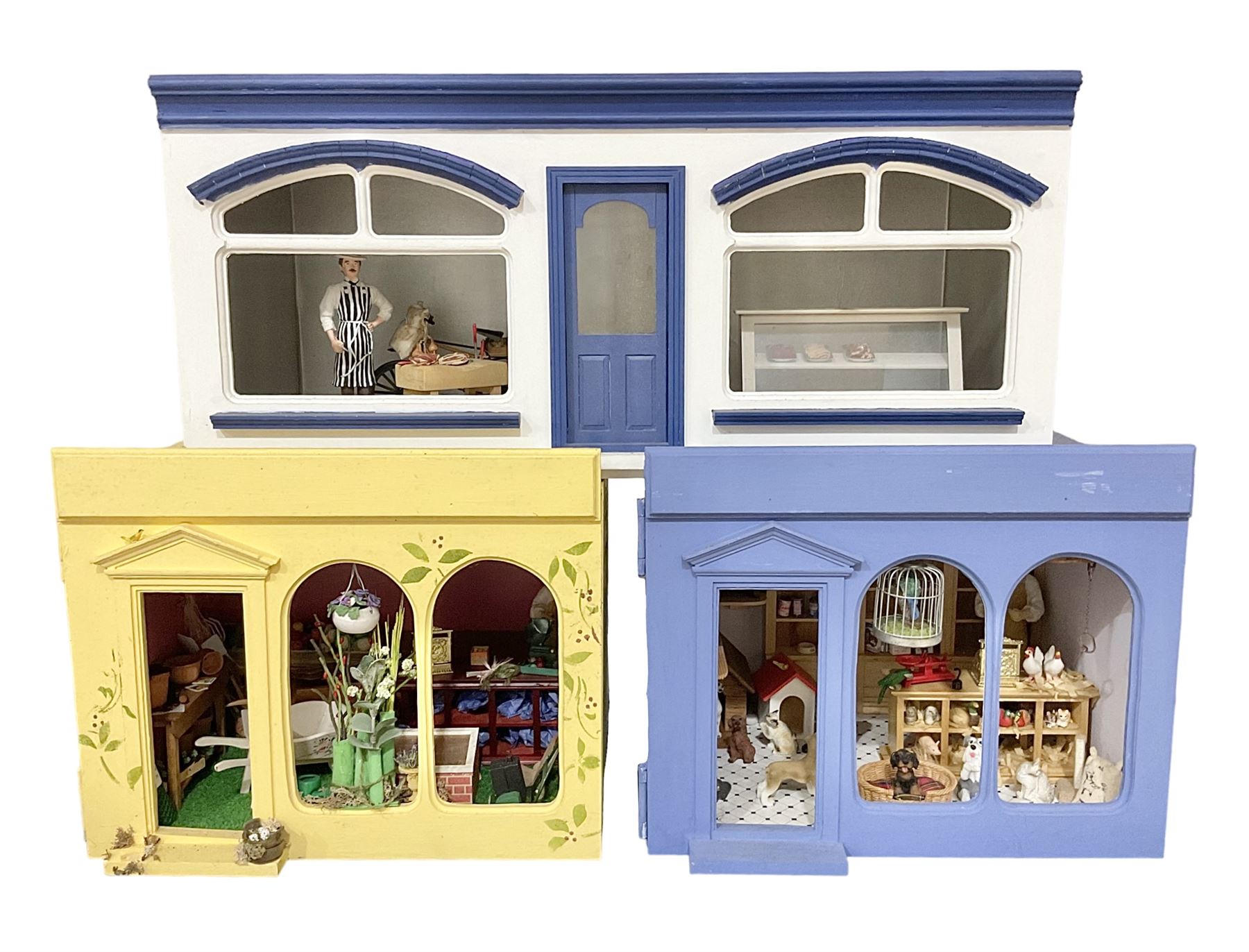 Three scratch-built wooden shop dioramas - single room Pet Shop with hinged front, fully furnished and well stocked with animals, birds and numerous accessories; and matching Garden Shop, fully furnished and well stocked with fruit, vegetables and garden accessories including lawn mower, wheelbarrows etc; each W34cm H27cm D26cm; and double fronted single room Butchers Shop with butcher at his block, partially stocked counter and two delivery cycles W57cm (3)