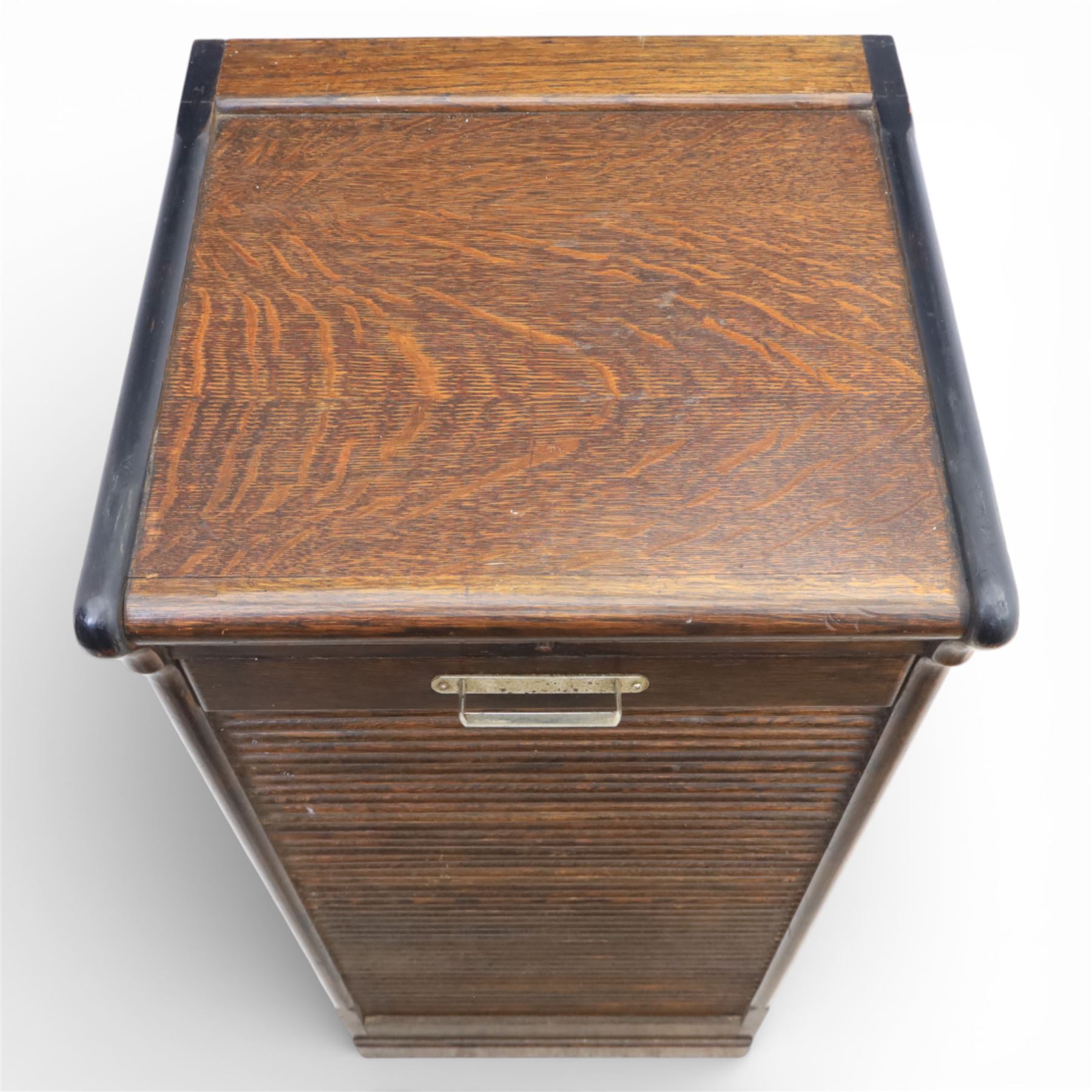 Early 20th century oak tambour front fitted cabinet, rectangular top with rounded corners over a roll tambour front enclosing a fitted interior of multiple shallow drawers with cut-out pulls, the sides with rounded uprights, on a stepped plinth base