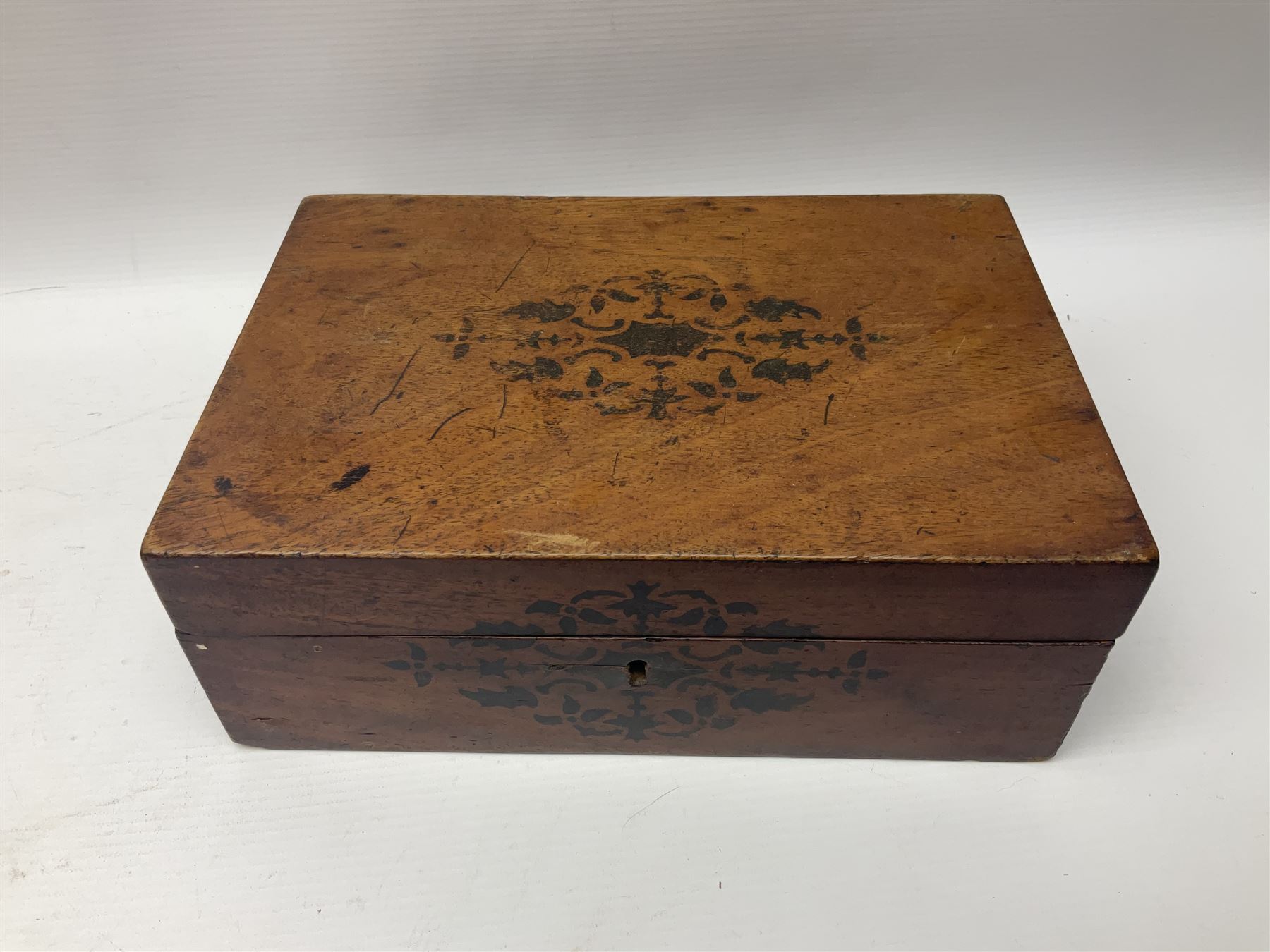 Walnut dressing table box, set with mother of pearl cartouche, opening to reveal a compartmentalised interior with mirror, covered in parts in purple velvet, together with a smaller jewellery box with stencil print, dressing table box H15cm